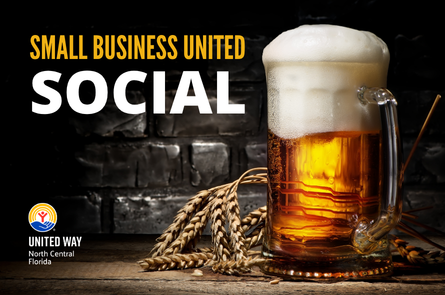 A foaming mug of beer sits on a wooden counter with a black brick backdrop.