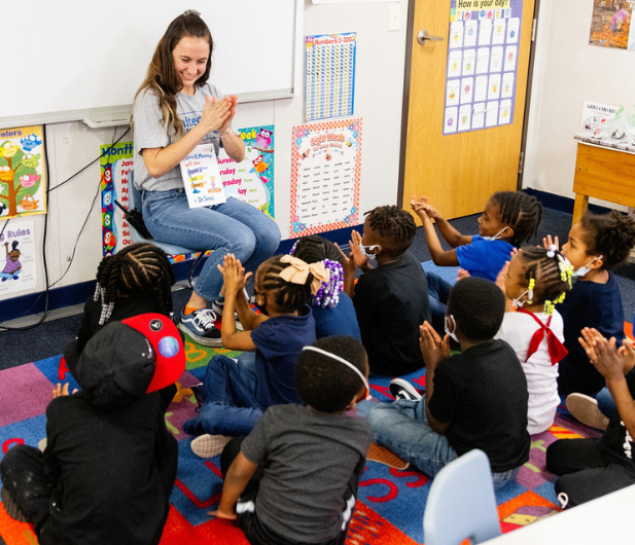 Young woman reading to elementary students